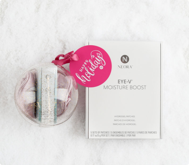 Neora’s hottest holiday must-have, the All Eyes on You Set, which includes Age IQ® Eye Serum, Eye-V™ Moisture Boost Hydrogel Patches and FREE Eye Mask laying on a bed of snow.